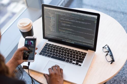 person hold gold htc android smartphone in front of macbook pro